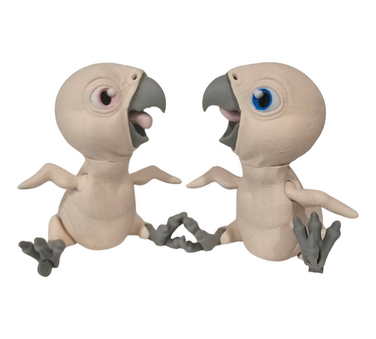 Two 3D-printed articulated bald parrots, one with blue eyes and one with pink eyes looking at each other with their cute mouths open